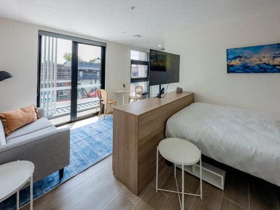 a bedroom with a bed and a desk and a living room