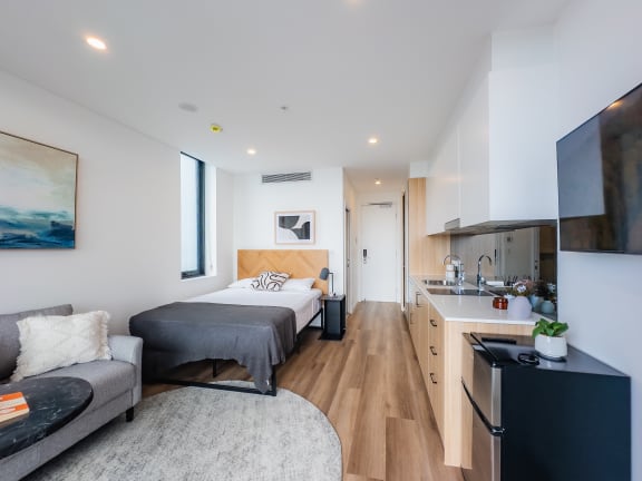 a bedroom with a bed and a kitchen with a sink