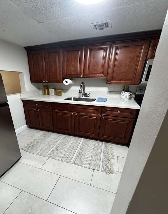 A kitchen with brown cabinets and a black refrigerator.