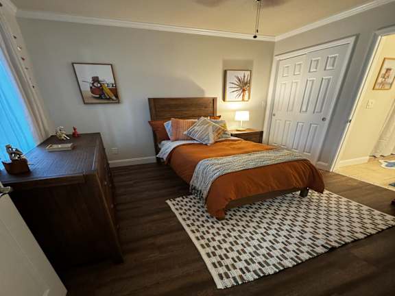 A bedroom with a bed, nightstand, and a ceiling fan.