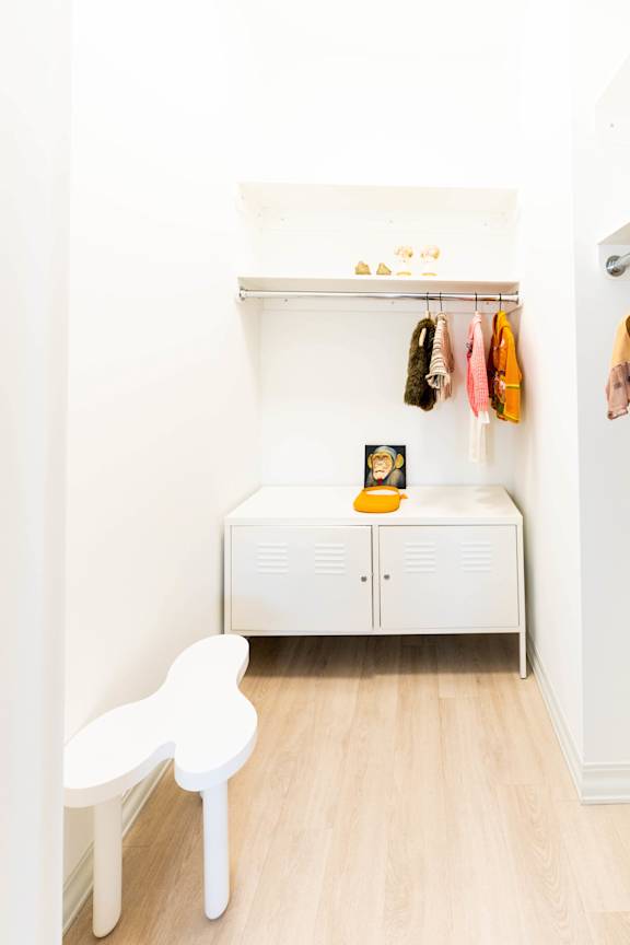 A white chair sits in a white room with a white bench and a white cabinet.