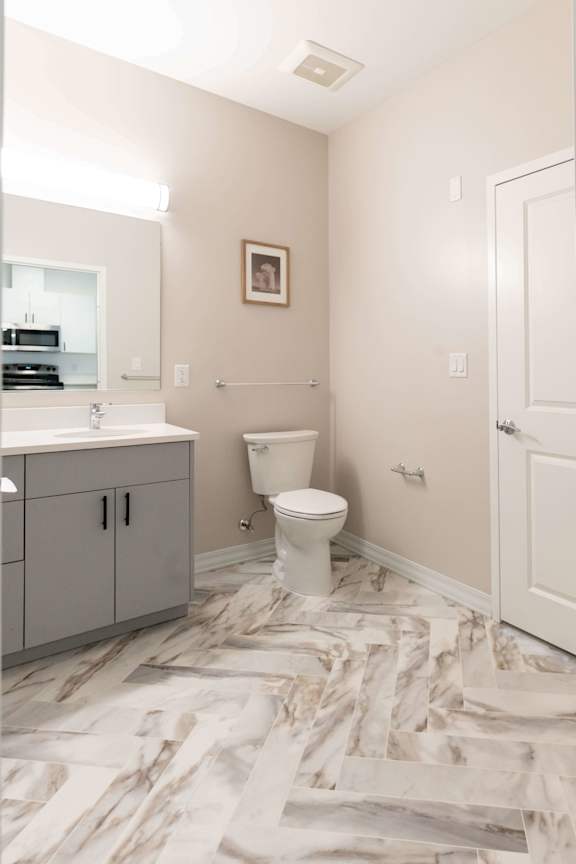 A bathroom with a toilet, sink, and a cabinet.
