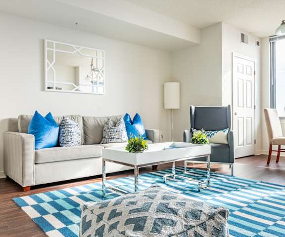 A living room with a white couch, a coffee table, and a blue rug.