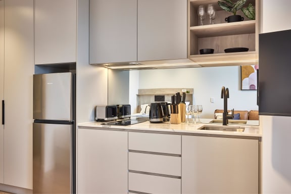 a kitchen with white cabinets and a stainless steel refrigerator and sink