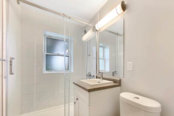 A white bathroom with a toilet, sink, and shower.