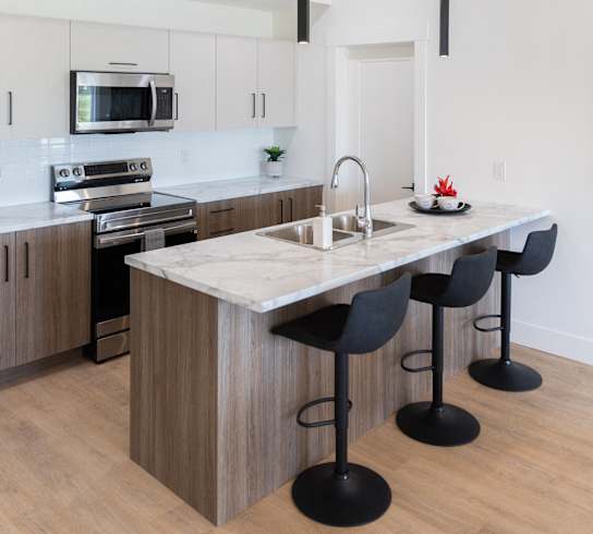 a kitchen with an island with a marble counter top and black stools