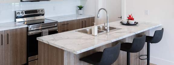 a kitchen with an island with a marble counter top and black stools