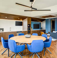 A modern dining room with a round table and blue chairs.