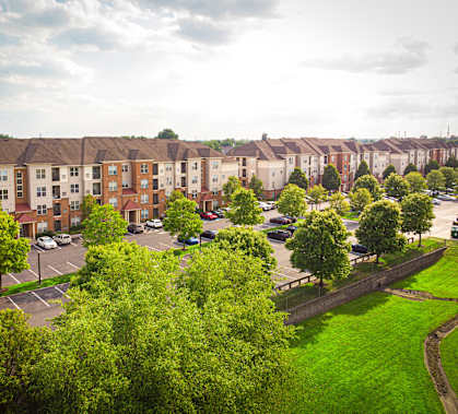 A row of apartment buildings with green trees in the foreground  at Bristol Station Apartments, Carteret, New Jersey
