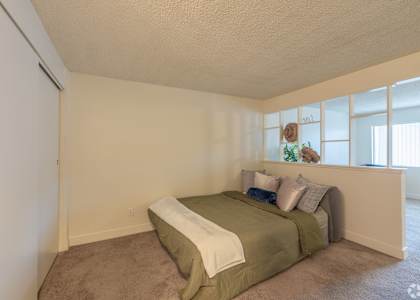 A bedroom with a bed and a carpeted floor.