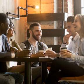 Five people sitting at a table drinking coffee.