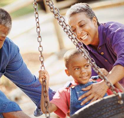 A man and a woman are playing with a child on a tire swing at Chapel Springs Apartments, Perry Hall, MD, 21128