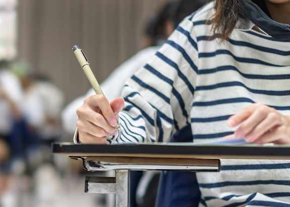 A person is writing on a piece of paper with a pen.