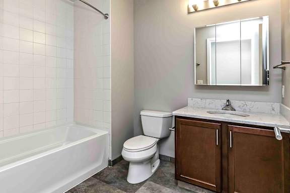 Bathroom with vanity and sink, mirrored medicine cabinet, and tub with tiled surround
