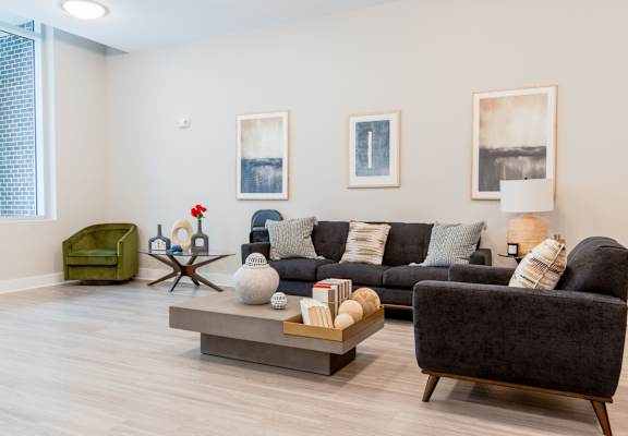 A living room with a grey couch, a green armchair, a wooden coffee table, and two framed pictures on the wall.