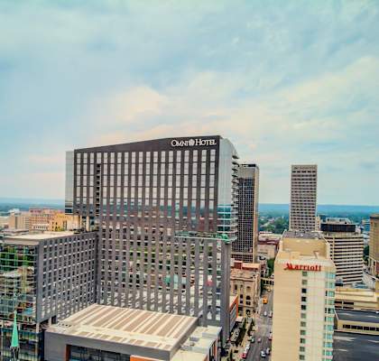 A cityscape with a large building in the foreground and a church with a green roof in the background.