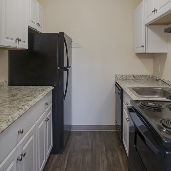 an empty kitchen with white cabinets and a black refrigerator and stove