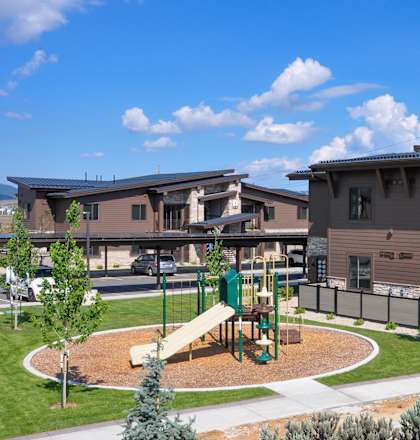A playground with a slide is in front of a building.
