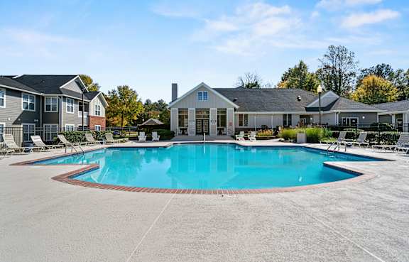 A large swimming pool in front of a building with a white fence around it.