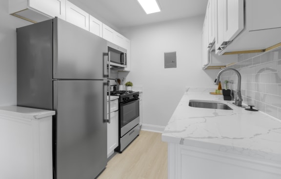 a kitchen with white countertops and stainless steel appliances