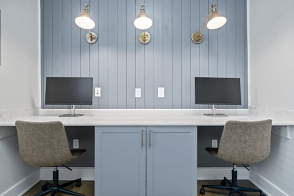 A white desk with a computer monitor and chair in front of a grey cabinet.
