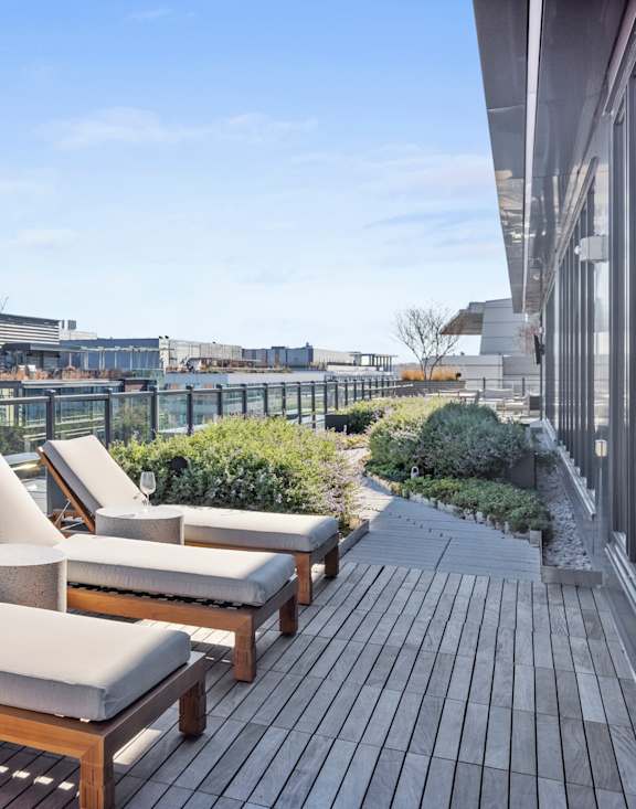 A rooftop patio with wooden furniture and a view of the city at Coda on Half Apartments, Washington, 20003