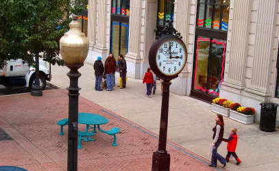 a clock on a pole on a sidewalk in front of a building