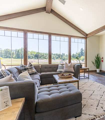 A living room with a stone fireplace and a large window at Riverplace Apartment Homes, Independence, OR