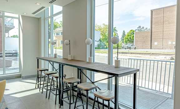 a long communal table with chairs in a room with large windows