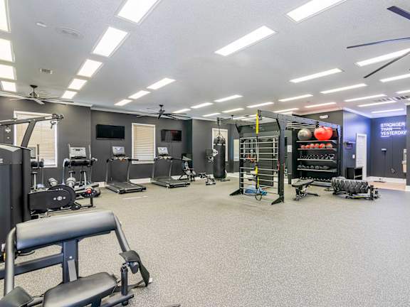 A gym with a variety of equipment including a leg press machine at Bedford Parke Apartments, Warner Robins, GA