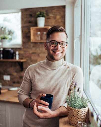 a man standing next to a window holding a coffee cup