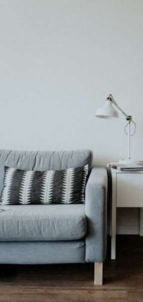 a living room with a couch and a table with a lamp