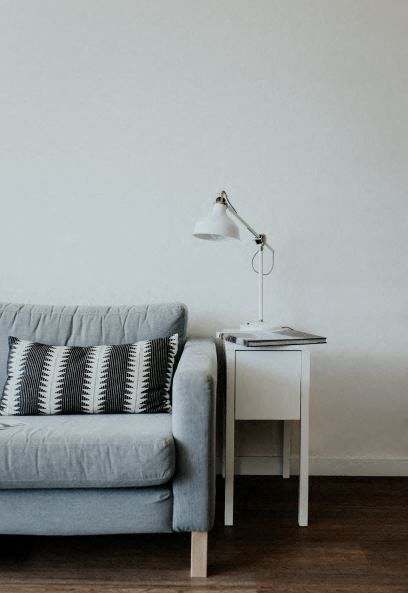 a living room with a couch and a table with a lamp