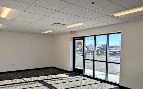 A room with a carpeted floor and a large window overlooking a parking lot.