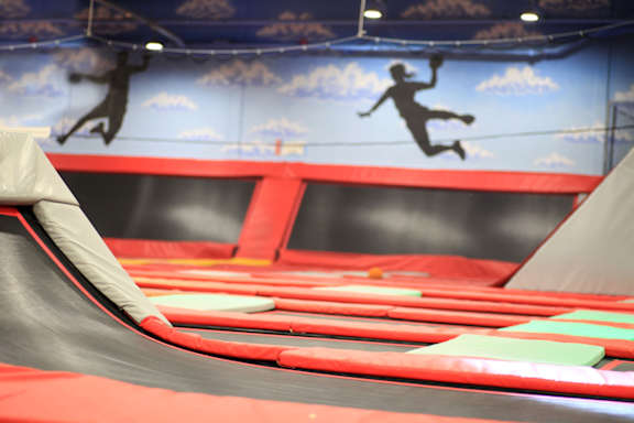 A trampoline park with a person jumping in the background.