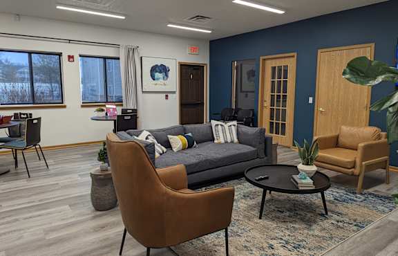 A living room with a grey couch, a brown chair, and a black coffee table.