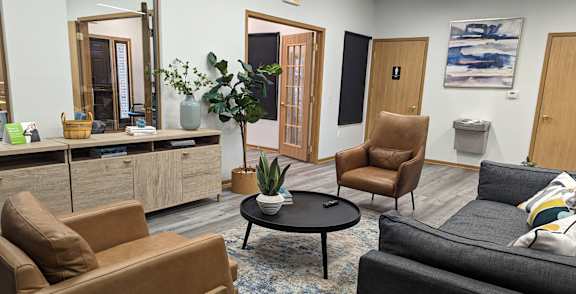 A living room with a brown couch, a black couch, and a coffee table.