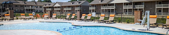 A large swimming pool with a concrete edge and a metal ladder.