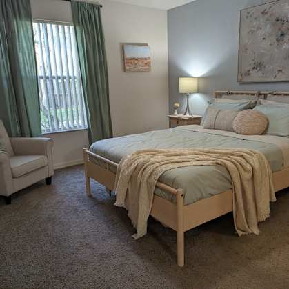 a bedroom with a bed and a chair and a window at Tivoli Apartments of Orlando, Oviedo, 32765
