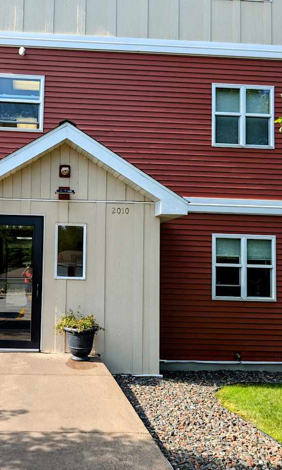 the front entrance of a red house with a porch