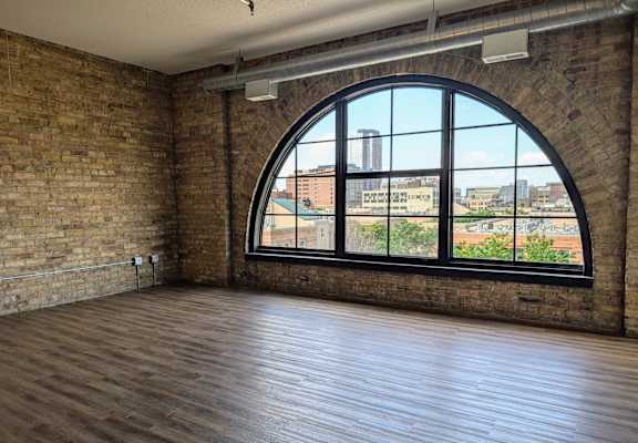 an empty room with a large window and wooden floors
