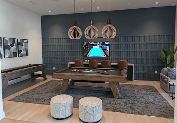 A room with a pool table and a TV mounted on the wall.