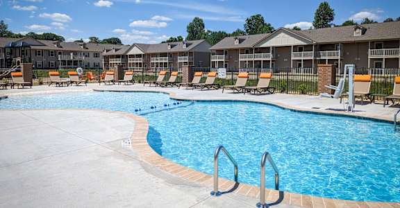 A large swimming pool with a concrete edge and a metal ladder.