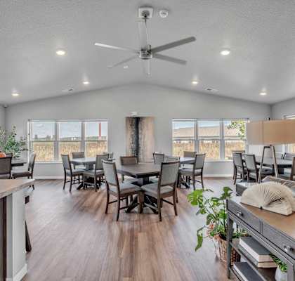 the gathering room has a large table with chairs and a ceiling fan