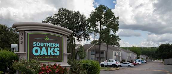 a sign for southern oaks apartments with a parking lot in the background