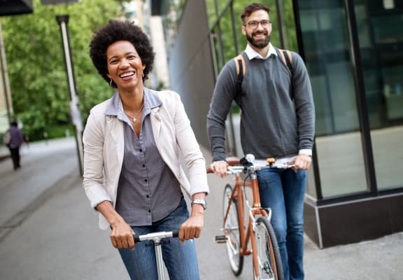 a man and woman walking their bikes down a city street