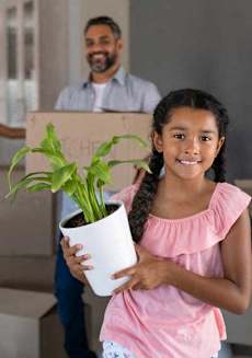 a girl holding a potted plant with a man holding a box