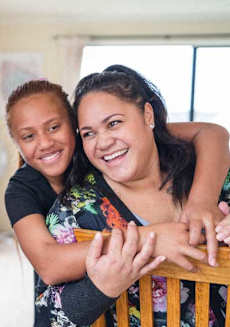 a woman and a girl sitting on a wooden chair