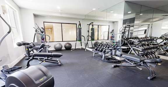 a gym with weights and other equipment on the floor and mirrored walls
