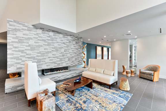 A modern living room with a stone fireplace and a blue rug. at Esprit Apartments, Marina del Rey, CA, 90292